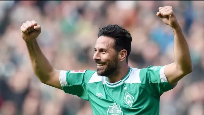 Claudio Pizarro lächelt und jubelt bei seinem Abschiedsspiel, umgeben von Fans und ehemaligen Kollegen. Eine wahre Bundesliga-Legende feiert seinen letzten Auftritt im Weser-Stadion.