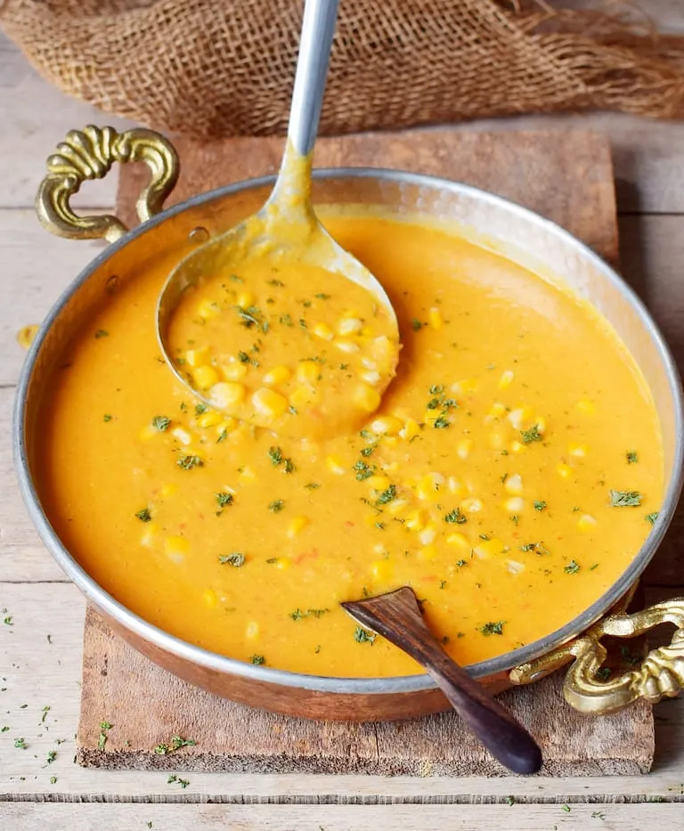 Cremige vegane Maissuppe in einer Schale mit Schöpfkelle, ideal für Sommer oder Winter mit frischem oder gefrorenem Mais.