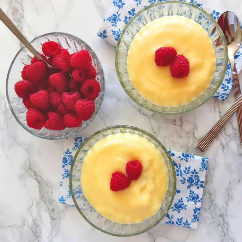 Cremiger Vanillepudding in Schalen mit frischen Himbeeren als Garnitur