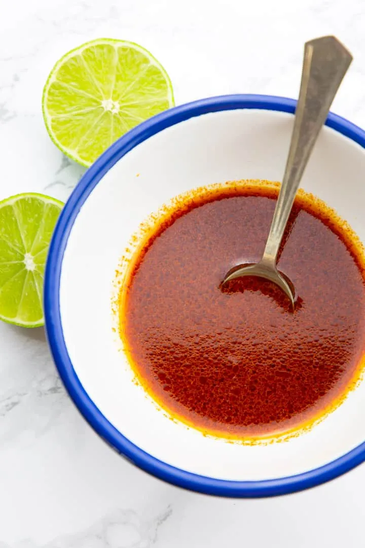 Cremiges Limetten-Koriander-Dressing in einer kleinen weißen Schüssel mit einem Löffel auf einer Marmoroberfläche