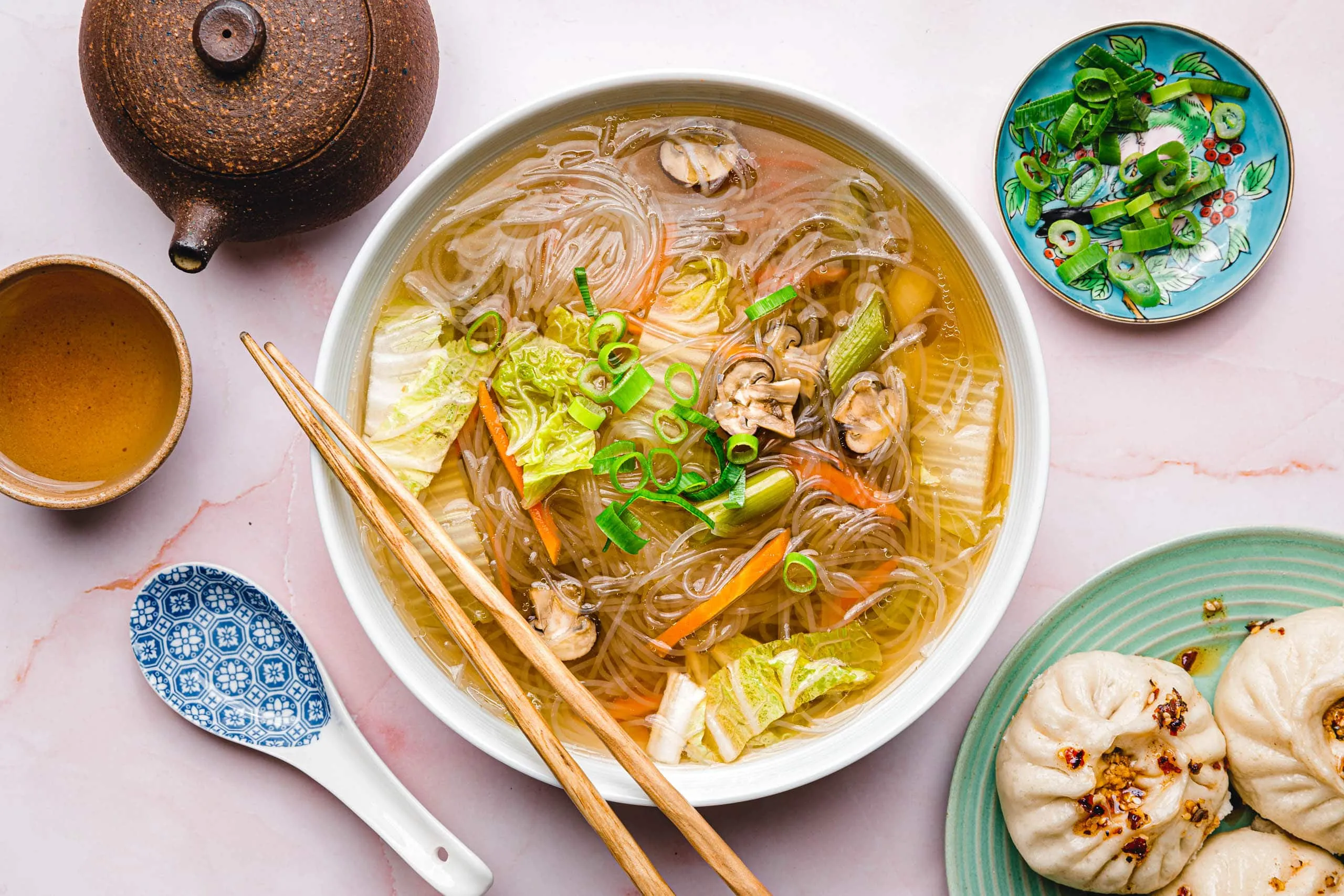 Dampfende Schüssel hausgemachter chinesischer Glasnudelsuppe mit frischen Kräutern und Chinakohl, servierbereit