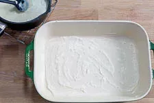 Das Einfetten der Auflaufform und Verteilen der ersten Schicht Béchamelsoße.