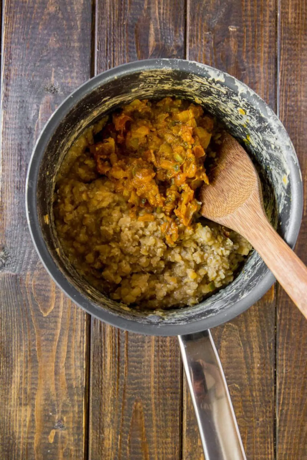 Das gewürzte Zwiebelgemisch wird in einen Topf mit roten Linsen gerührt, um ein cremiges und geschmackvolles Indisches Dal zuzubereiten.