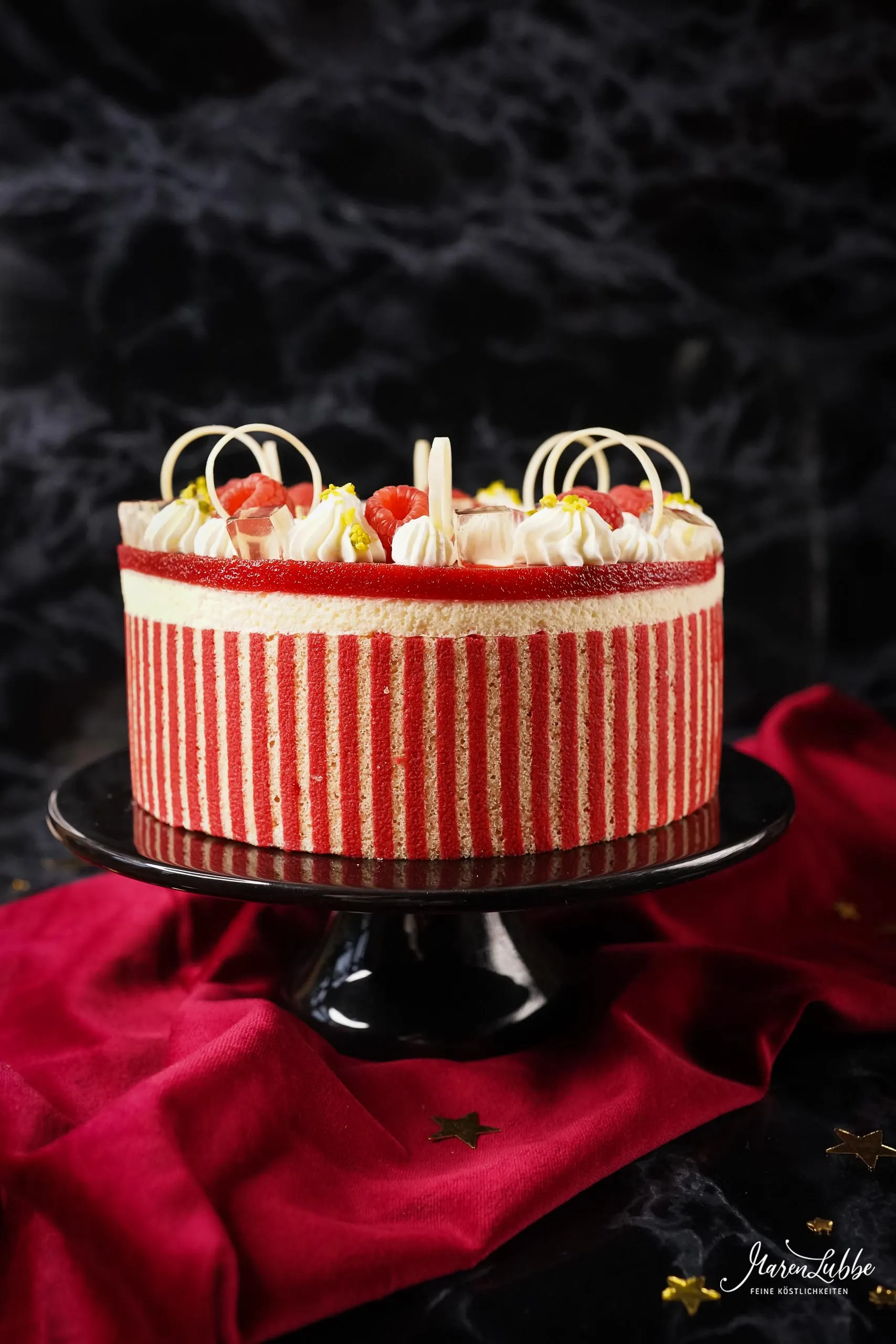 Dekorierte feine Geburtstagstorte mit frischen Himbeeren und Pistazien