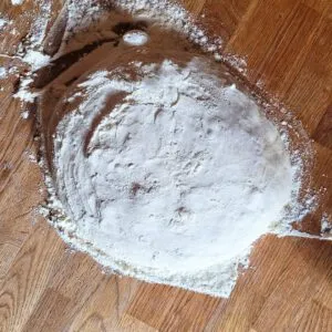 Den Sauerteig-Ciabatta-Teig vorsichtig auf eine bemehlte Arbeitsfläche stürzen