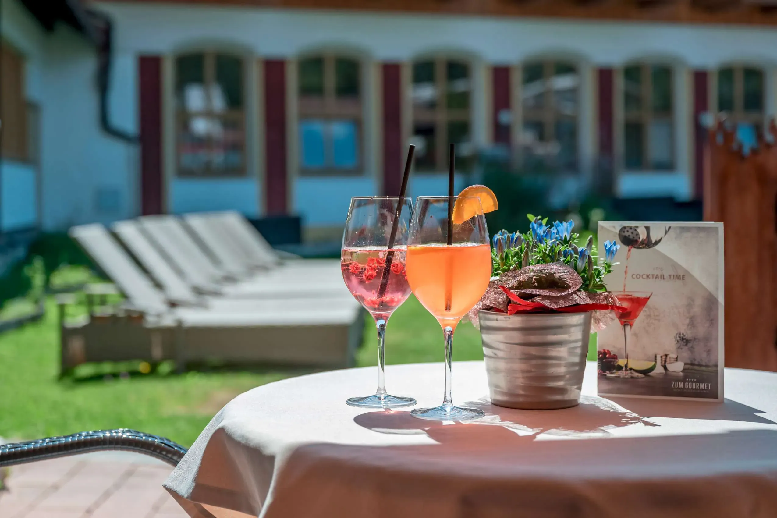 Der einladende Gartenbereich mit Gastronomie im Hotel Zum Gourmet, wo Gäste und ihre Hunde gemeinsam die alpine Atmosphäre genießen können.