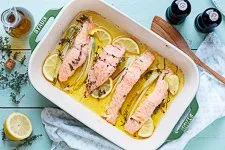 Der fertig gegarte Zitronenlachs im Ofen, servierfertig in der Auflaufform, mit frischem Baguette und Kräutern. Ein Beispiel für köstliche Lachsgerichte.