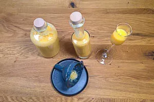 Der fertige, goldene Eierlikör wird mithilfe eines Trichters sorgfältig in Glasflaschen abgefüllt.