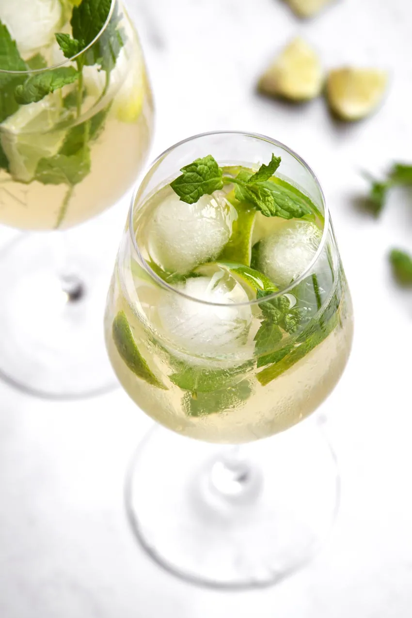 Der klassische Hugo Spritz Cocktail, appetitlich angerichtet mit Holunderblütensirup, Prosecco und Garnitur