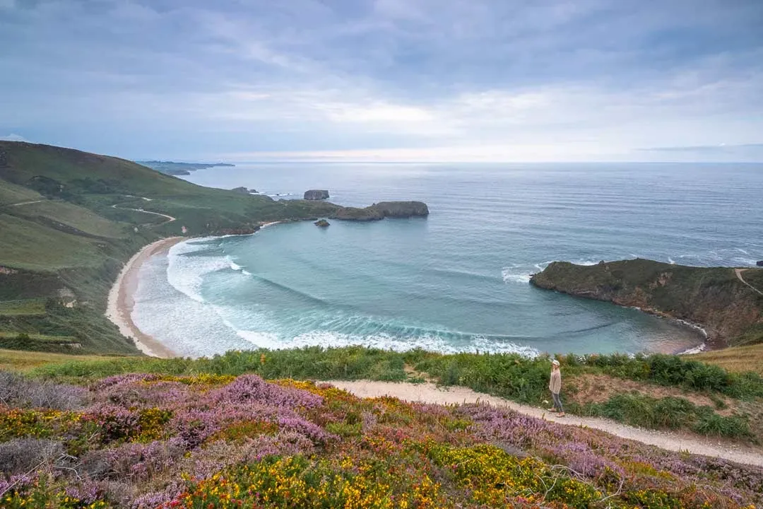 Der malerische Playa Torimbia in Nordspanien, ein unberührter Strand umgeben von grünen Hügeln.