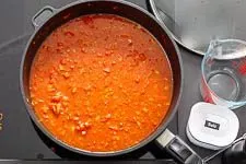 Der Reis, Ajvar und Tomatenmark werden zur Gemüsebasis gegeben, bevor alles mit Gemüsebrühe abgelöscht und zum Köcheln gebracht wird.