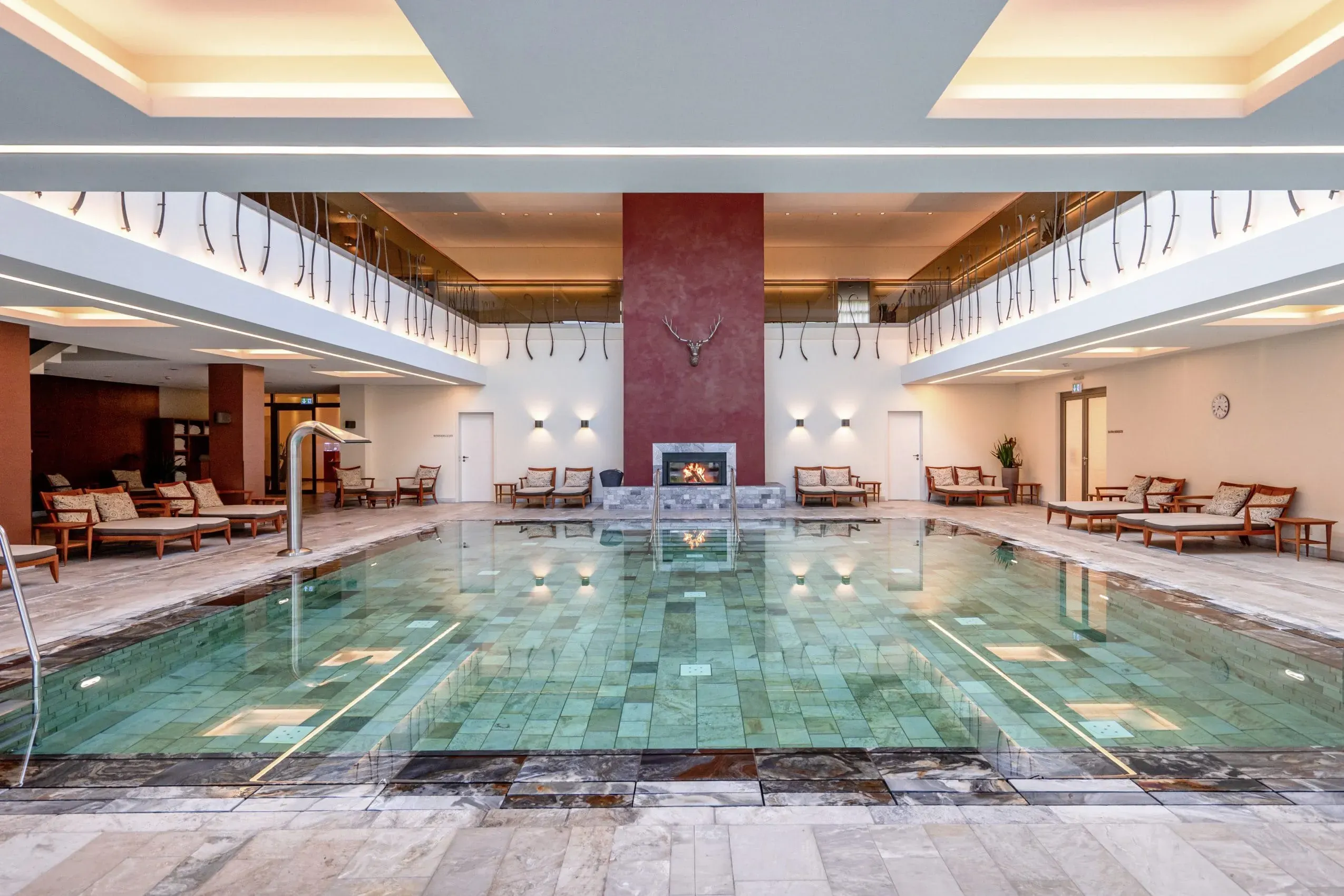 Der stilvolle und beleuchtete Indoor-Pool mit Kamin und bequemen Liegen im Wald- &amp; Schlosshotel Friedrichsruhe, einem exklusiven Hotel mit Hund.