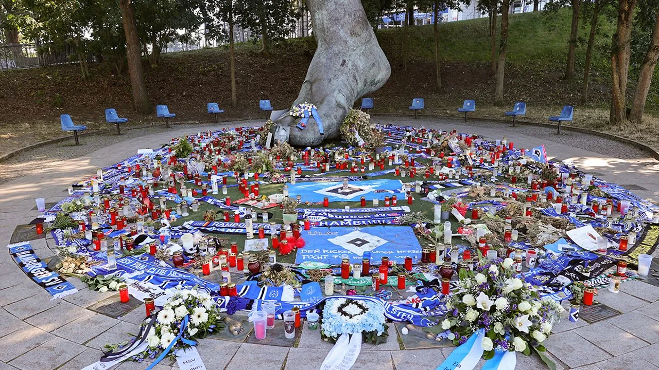 Der Uwe Seeler Bronze-Fuß bedeckt mit Blumen, Kerzen und Trauerkränzen