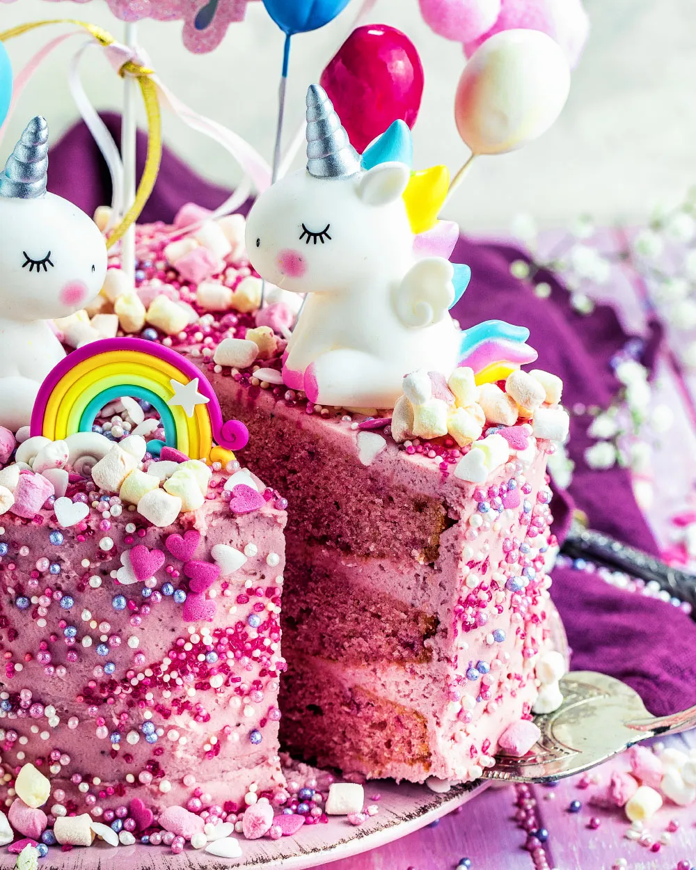 Detailansicht der Einhorn-Kuchen-Dekoration mit Spielzeugfiguren und Regenbogen-Elementen