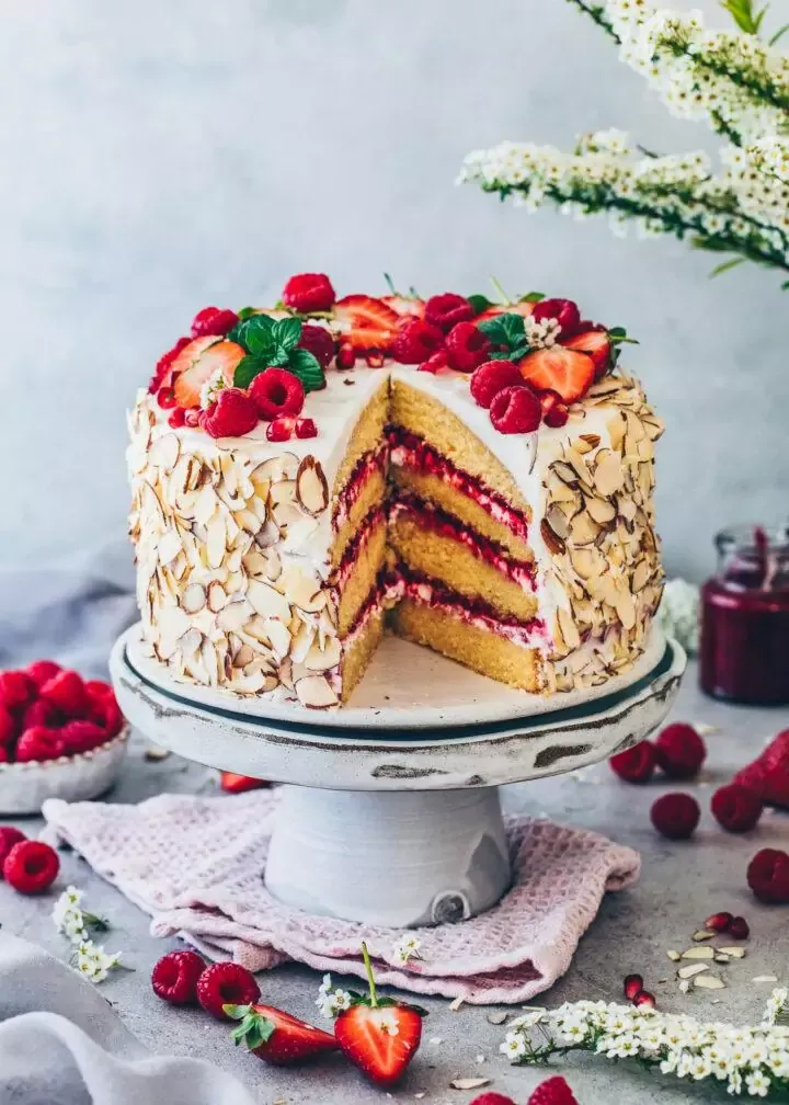 Detailansicht der Garnierung einer veganen Himbeer-Sahnetorte mit Beeren und Granatapfelkernen.