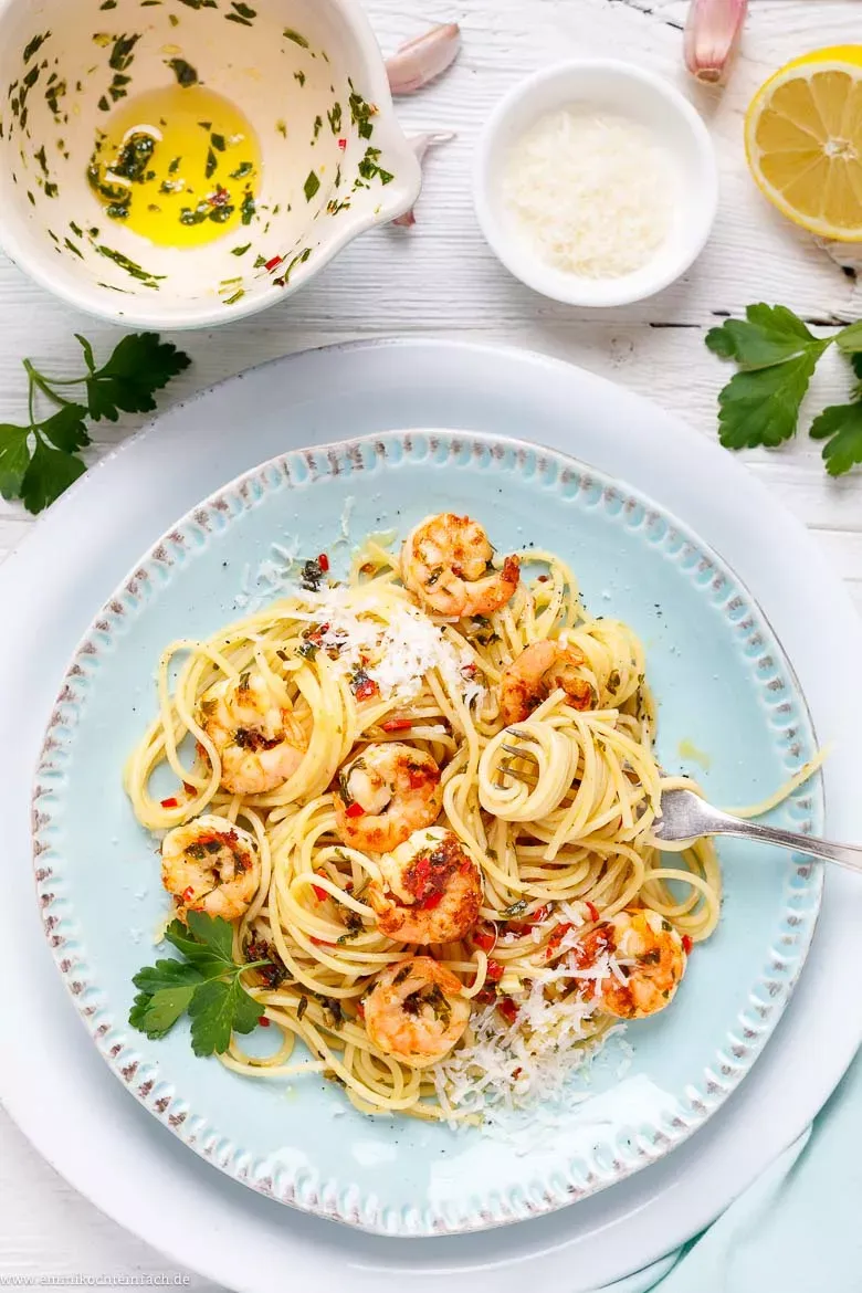 Detailaufnahme von Spaghetti mit Garnelen und frischen Kräutern in einer Servierschale, ein Gericht, das auch in Deutschland leicht selbstgemacht werden kann.