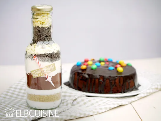 Detaillierte Ansicht einer selbstgemachten Geburtstagskuchen Backmischung im Glas, fertig zum Verschenken mit einer kleinen Kerze.