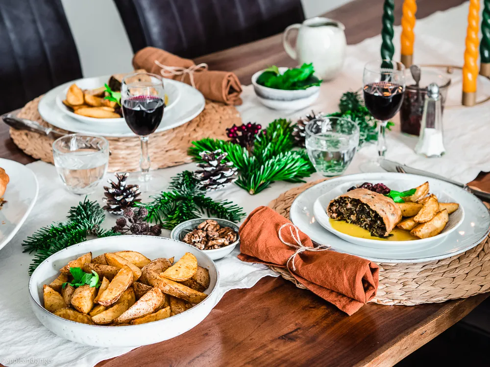 Deutsches Weihnachtsmenü mit Grünkohlstrudel, Ofenkartoffeln und Cranberry-Apfel-Chutney auf einem festlichen Tisch
