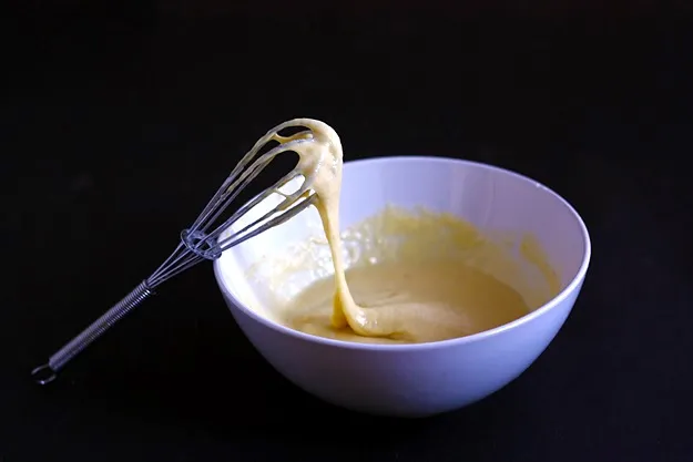 Dicker Palatschinkenteig in einer Schüssel mit Schneebesen, um Klümpchen zu vermeiden