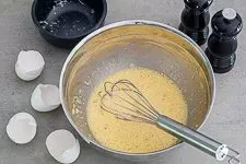 Die cremig verquirlte Ei-Käse-Mischung mit frisch gemahlenem Pfeffer, bereit für die Zubereitung der Carbonara Soße.