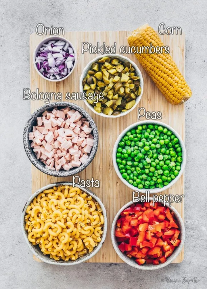 Die frischen Zutaten für den veganen Nudelsalat: Nudeln, vegane Wurst, Gurken, Erbsen, Mais, Zwiebeln und Paprika.