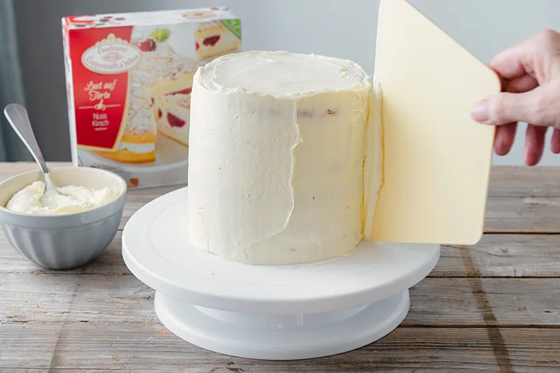 Die gesamte Geburtstagstorte mit einer glatten Sahneschicht umhüllen