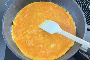 Die Omelett-Eiermasse zieht in der Pfanne an, wird leicht gerührt, um ein fluffiges und lockeres Ergebnis zu erzielen.