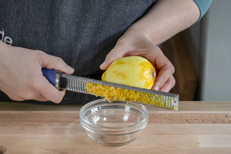 Die Schale einer Zitrone wird fein abgerieben