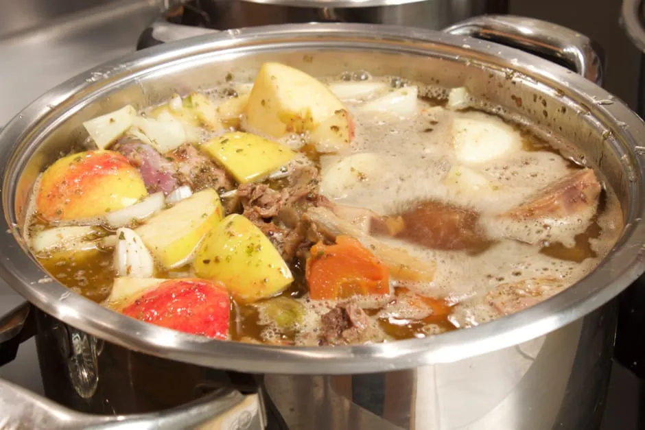 Die Zubereitung einer cremigen Gänsesauce in einem Topf, mit Knochen und Gemüse.