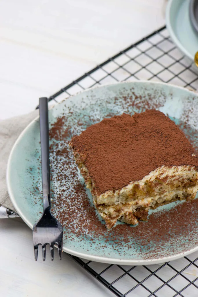 Die Zubereitungsschritte von Tiramisu ohne Alkohol in einer Auflaufform, mit Löffelbiskuits und Mascarpone-Creme, die den Amaretto Ersatz durch Bittermandelaroma nutzt.