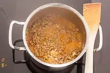 Die Zugabe von Hackfleisch und Gewürzen zur Bolognese Soße im Topf.