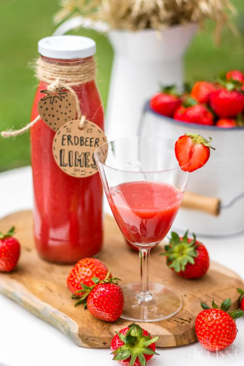 Drei gefüllte Erdbeerlimes-Flaschen in einem Holzkasten, bereit zum Genuss