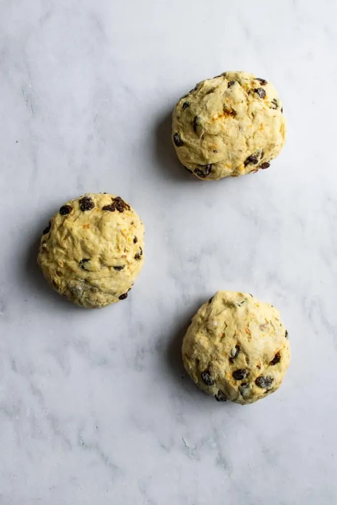 Drei gleichgroße Teigkugeln für den Osterkranz auf einer Marmorfläche, nach dem ersten Gehen und Teilen des Teigs.