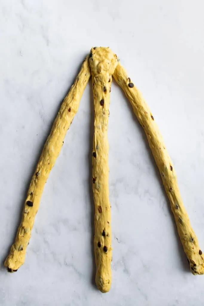 Drei gleichmäßig gerollte Teigstränge für den Osterkranz, bereit zum Flechten auf einer Arbeitsfläche.