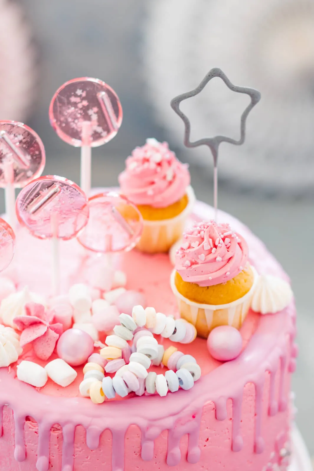 Drei Schichten eines Drip Cakes, elegant dekoriert mit Beeren und Süßigkeiten, bereit für einen besonderen Anlass.