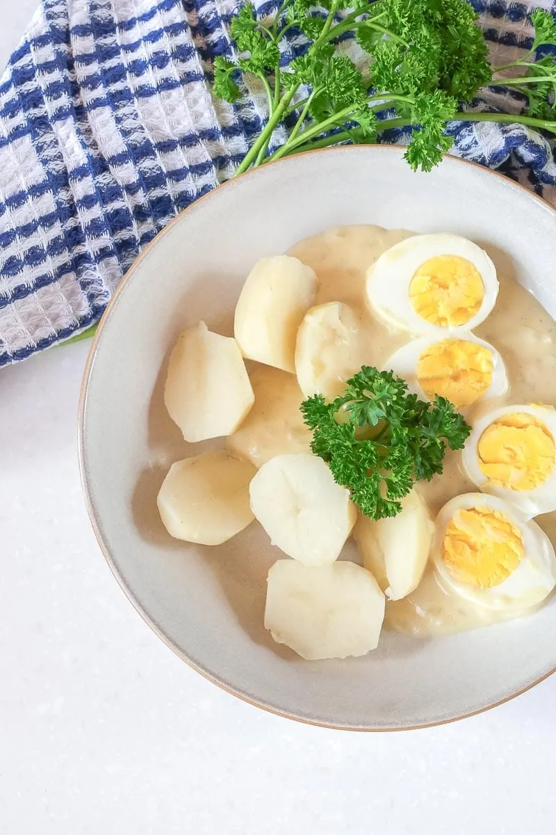 Eier in Senfsoße mit frischer Petersilie und Salzkartoffeln in einer rustikalen Schüssel