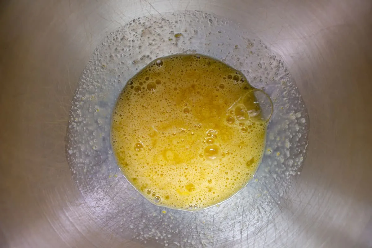 Eier und Zucker in einer Metallschüssel zusammengeschlagen.