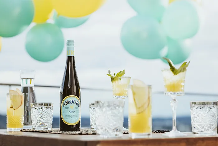 Ein Amouro Spritz in einem Rotweinglas, garniert mit einer Orangenscheibe