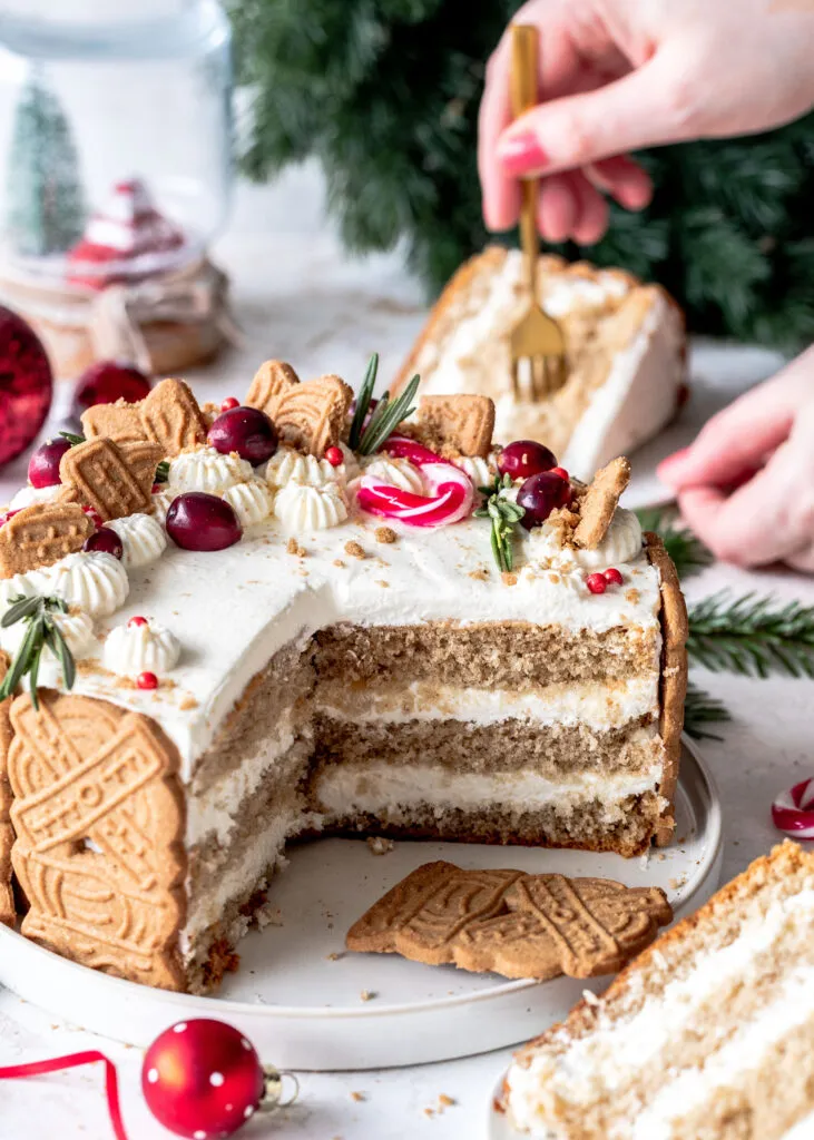 Ein angeschnittenes Stück Bratapfel-Spekulatius-Torte zeigt die Schichten aus fluffigem Spekulatius-Biskuit und cremiger Bratapfel-Quarkfüllung.