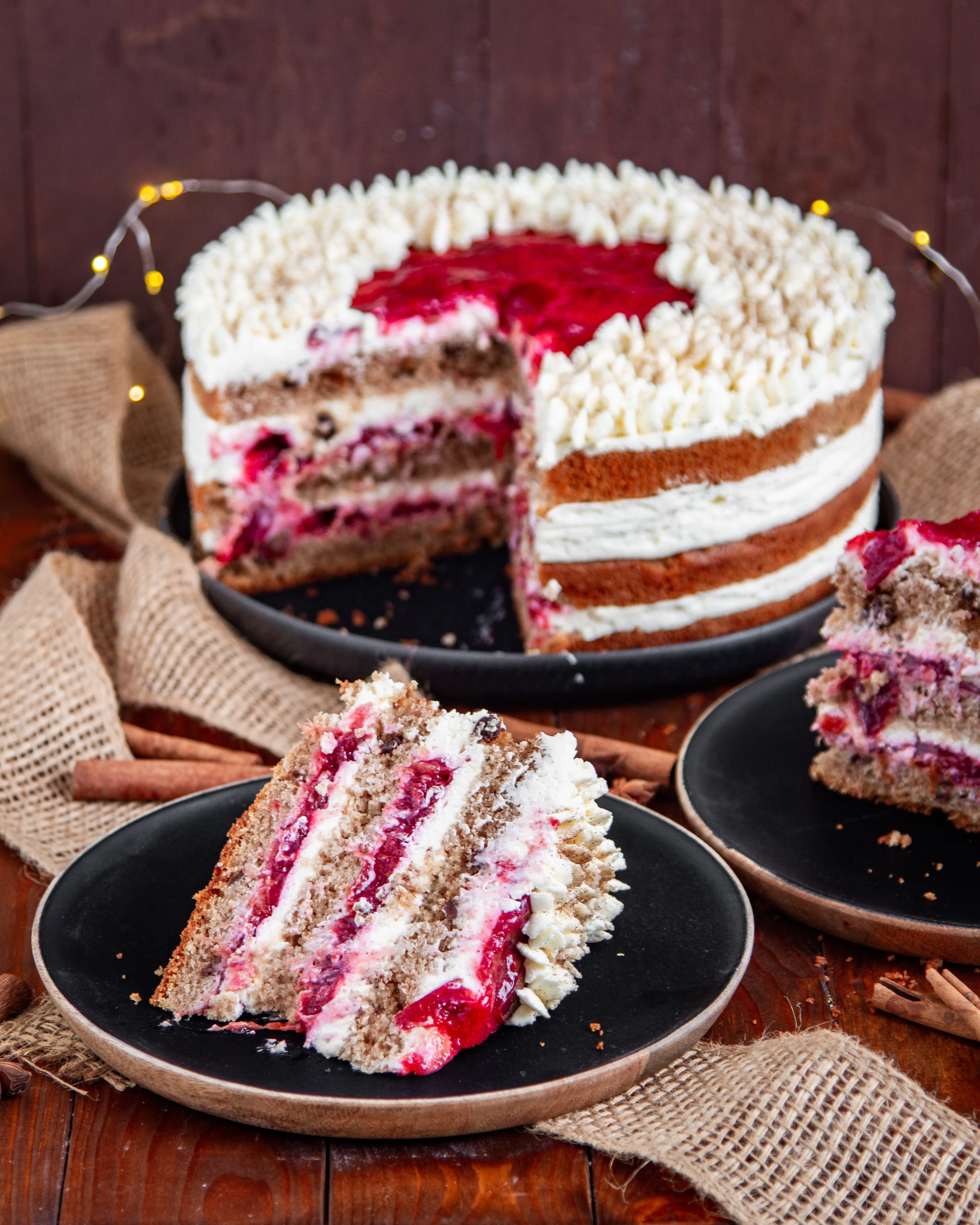 Ein Anschnitt der Spekulatius-Zimt-Sahne-Torte, der die Schichten aus fluffigem Boden, cremiger Mascarpone und Zimtpflaumen zeigt.
