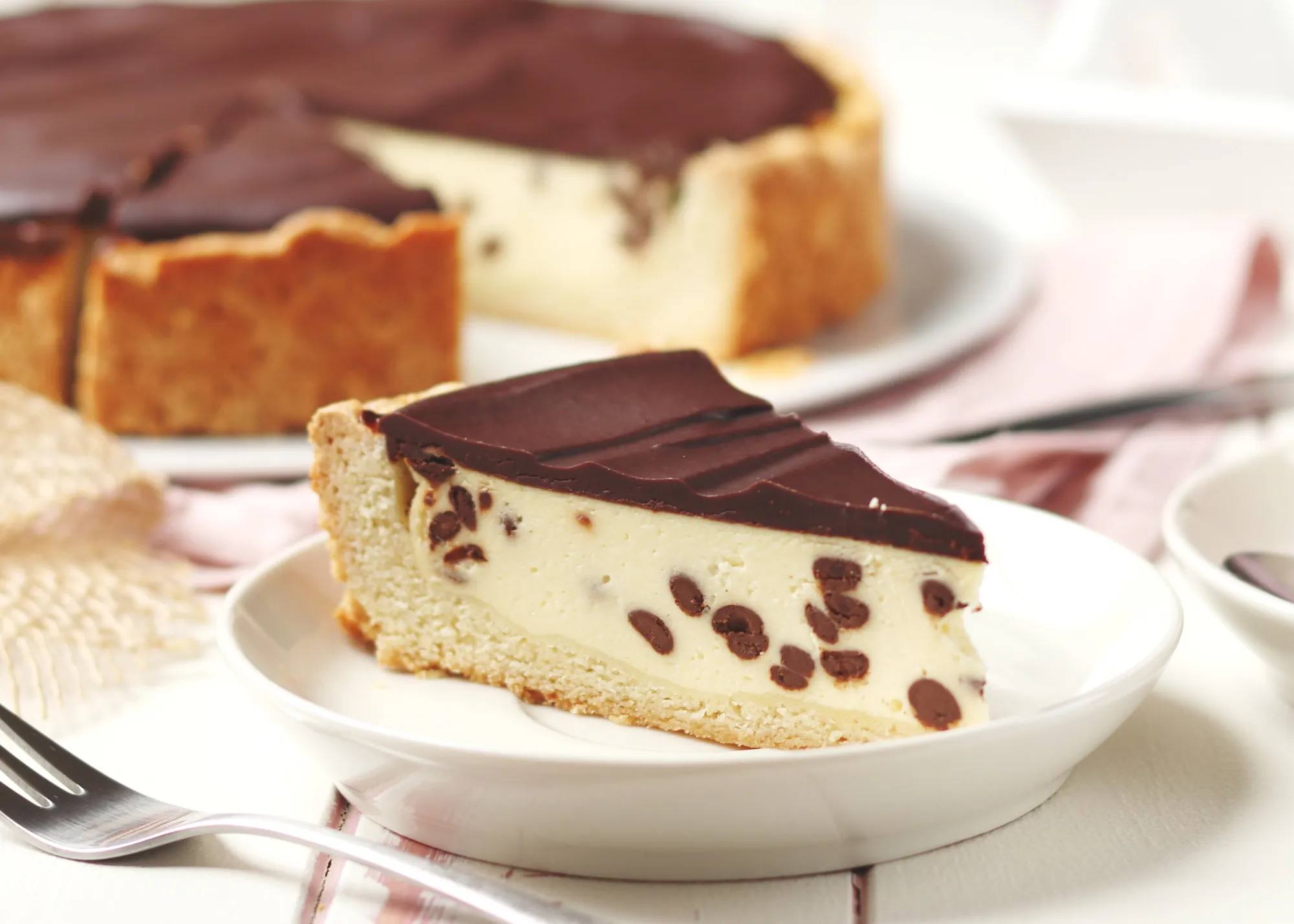 Ein appetitliches Stück cremiger Käsekuchen mit Schokolade und glänzender Ganache, servierfertig.