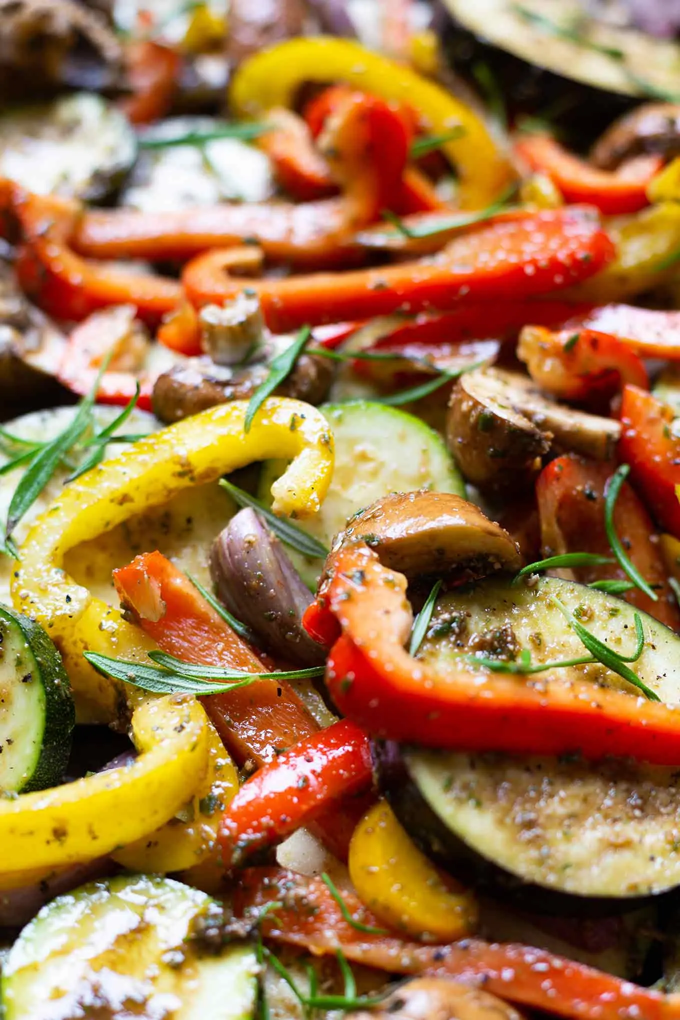 Ein Backblech voller Antipasti mit den vorbereiteten Schalotten und Rosmarinzweigen