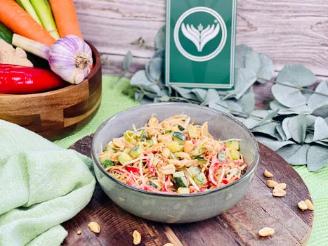 Ein bunter Glasnudelsalat mit frischem Gemüse und Erdnusssauce in einer Schüssel