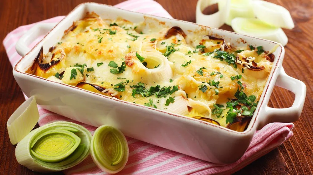 Ein cremiger Kartoffel-Lauch-Auflauf in einer Auflaufform, bestreut mit Käse.