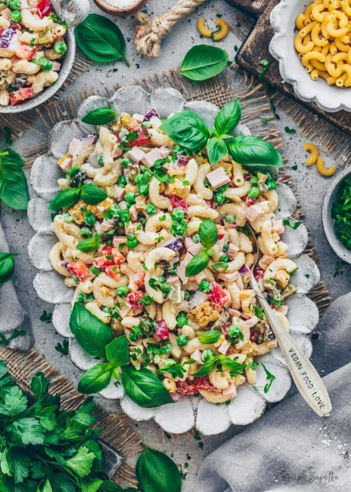 Ein cremiger veganer Nudelsalat nach Omas Art, servierfertig in einer rustikalen Schüssel.