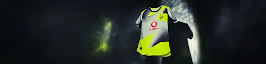 Ein Detail des Borussia Dortmund Auswärtstrikots 25/26, das das Vereinswappen und Sponsorenlogos zeigt.