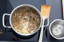 Ein Detailbild der Zubereitung, wo Risotto-Reis mit Flüssigkeit verrührt wird