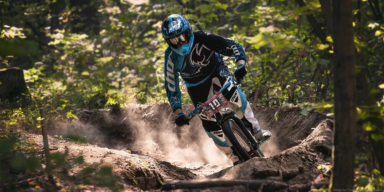 Ein Downhill-Biker fährt schnell durch einen Wald mit Hindernissen