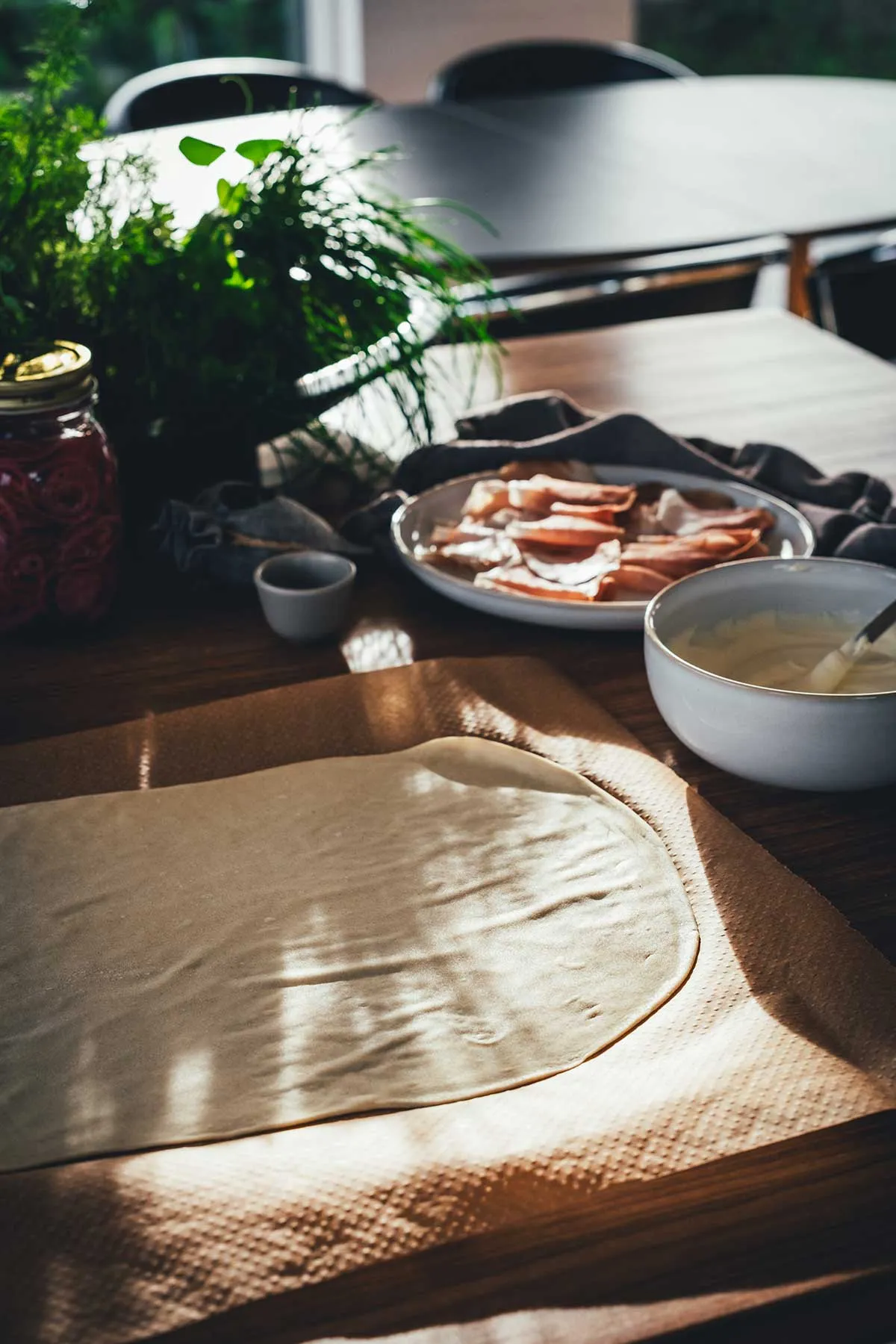 Ein dünn ausgerollter Flammkuchenteig, bereit für den Belag