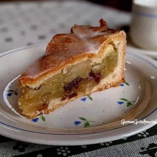 Ein einzelnes Stück Gedeckter Apfelkuchen, das mit Puderzucker bestreut ist und die perfekte Balance zwischen süßem Apfel und knusprigem Teig demonstriert.